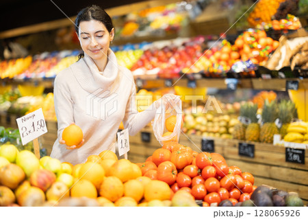 Woman putting oranges in a bag in a store Woman putting oranges in a bag in a store 128065926