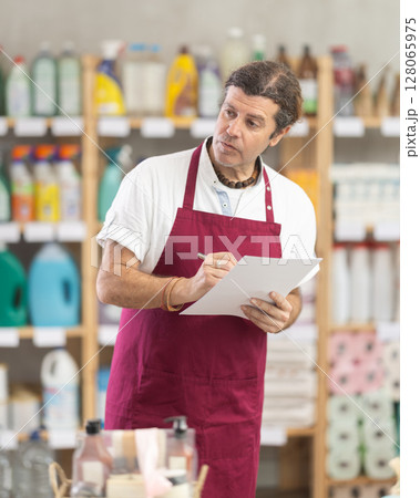 Adult man seller conducting inventory in store 128065975