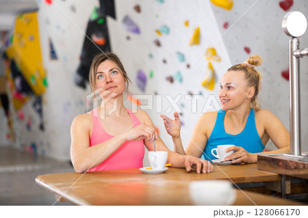 Two sports women drink tea or coffee after training on climbing wall 128066170
