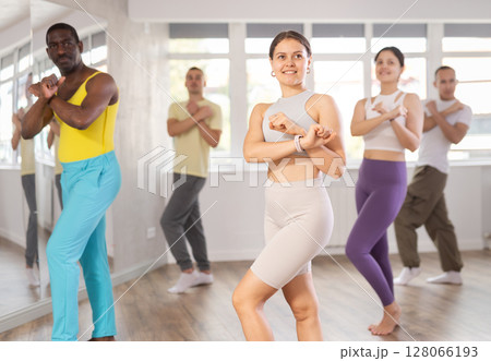 Active female Hip-hop dancers exercising dance moves in studio with multinational group 128066193