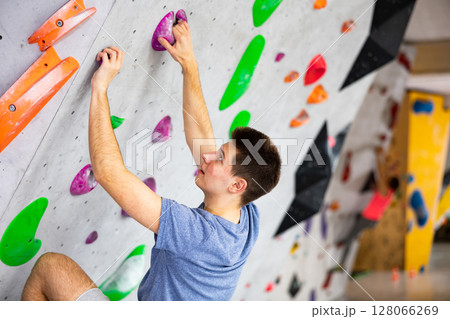 Man training at bouldering gym without special climbing equipment 128066269
