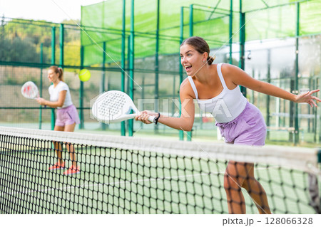 Active womans with enthusiasm playing padel on tennis court 128066328