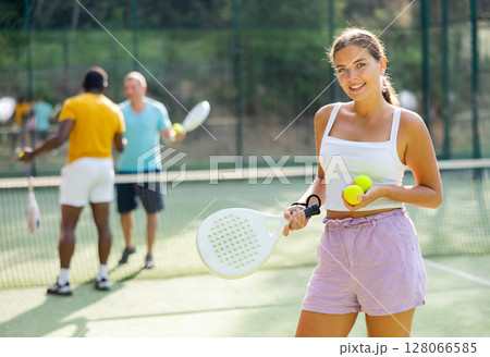 Woman posing with racket and ball in hands on padel court 128066585