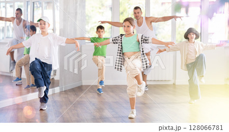 Group of young girls and boys in casualwear performing contemporary street dance in training room Group of young girls and boys in casualwear performing contemporary street dance in training room 128066781
