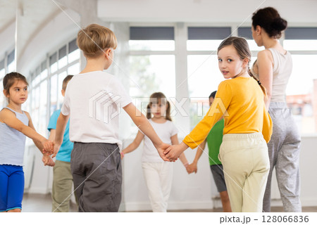 Group of young children dance in ring during dance class with woman teacher 128066836