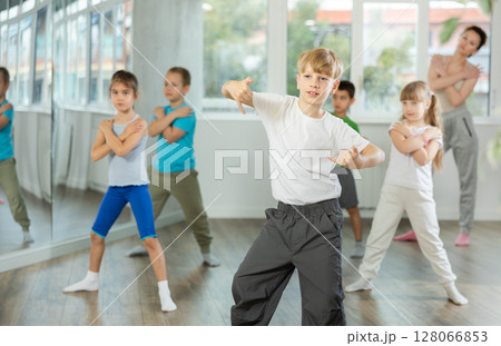 Boy learn to dance modern dances, repeat movement with unrecognizable teacher. 128066853