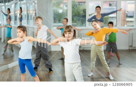 Girl learn to dance modern dances, doing movement with unrecognizable teacher. 128066905