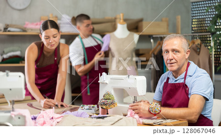 Senior man employee sewing, stitch clothes, guy work with mannequin, girl draw dress pattern 128067046