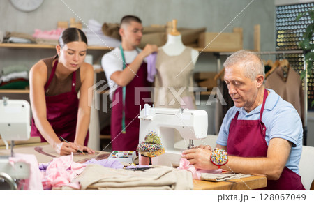 Senior man employee sewing, stitch clothes, guy work with mannequin, girl draw dress pattern 128067049