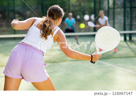 Woman playing padel tennis match during training on court 128067147
