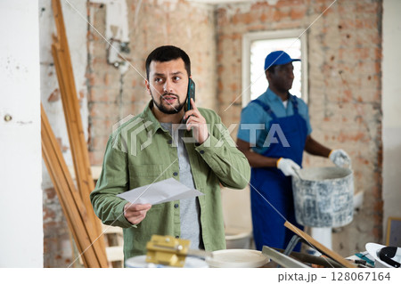 Man architect having telephone conversation about project documentation Man architect having telephone conversation about project documentation 128067164