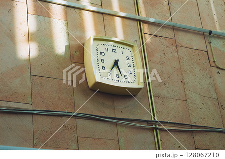 An old working clock hangs on the wall in a production room An old working clock hangs on the wall in a production room 128067210