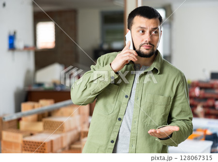 Owner of building under construction inspects the room being renovated and talks on mobile phone Owner of building under construction inspects the room being renovated and talks on mobile phone 128067315