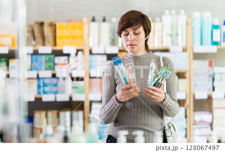 Female customer choosing toothbrushes in drugstore Female customer choosing toothbrushes in drugstore 128067497