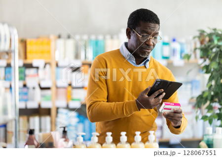 African American scanning barcode on paracetamol box with phone at pharmacy African American scanning barcode on paracetamol box with phone at pharmacy 128067551