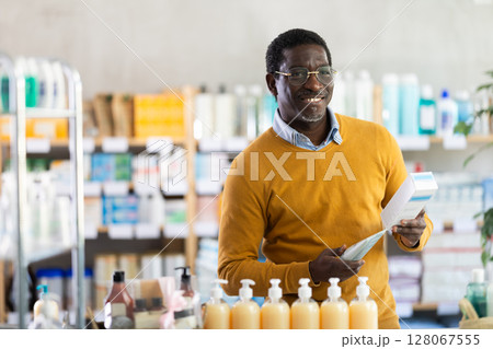 Cheerful African American man choosing nourishing cream in drugstore Cheerful African American man choosing nourishing cream in drugstore 128067555