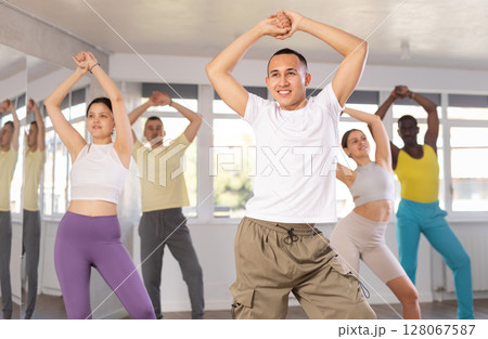 Young Asian male instructor leading modern dance class Young Asian male instructor leading modern dance class 128067587