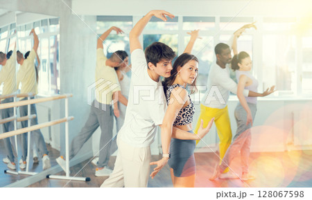 Group of men and women in sportswear learning to dance latin dances in dance studio 128067598