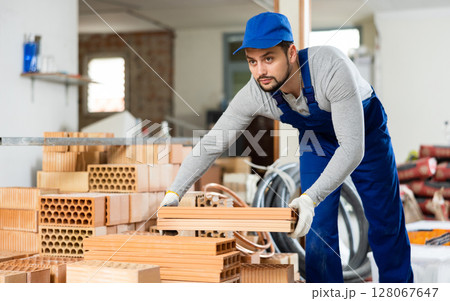 Young man stacking bricks at construction site Young man stacking bricks at construction site 128067647