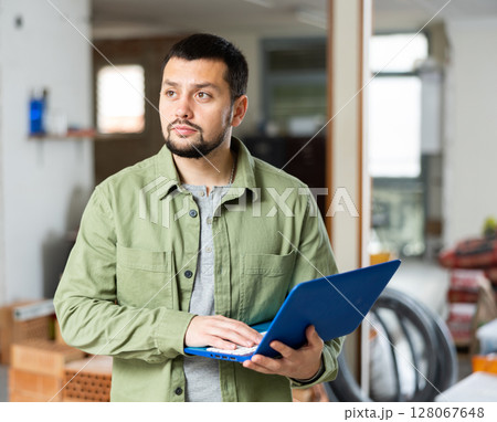 Interested young man using laptop in house during renovation 128067648