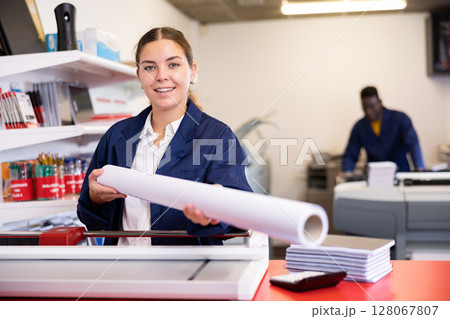 Happy young female specialist in a blue uniform holding whatman in a roll in the typography 128067807