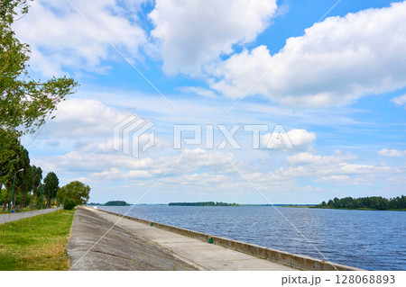 Stone river embankment overgrown with green bushes for walk 128068893
