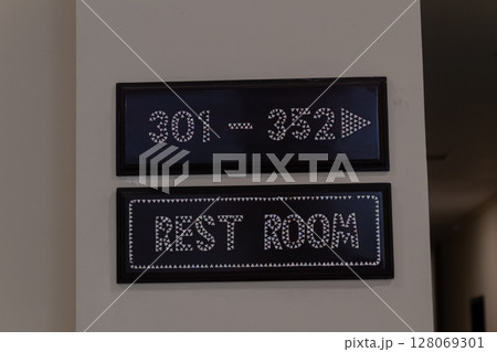 Directional wall signs showing room numbers 301 to 352 and rest room location 128069301