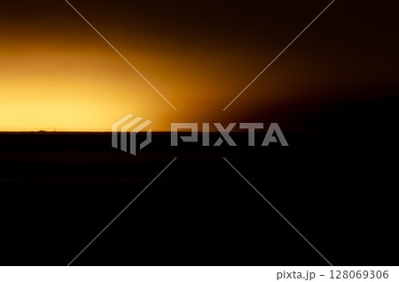 Abstract composition of warm golden light across a dark horizon line 128069306