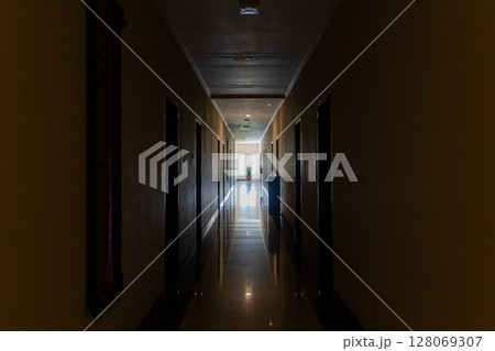 Long empty hallway stretching into the distance towards a bright illuminated window Long empty hallway stretching into the distance towards a bright illuminated window 128069307