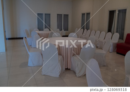 Clean and neat event space with white covered chairs ready for guests Clean and neat event space with white covered chairs ready for guests 128069318