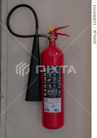Red Fire Extinguisher Mounted on Wall for Emergency Fire Safety at Mataram, Indonesia on November 9, 2024 128069341