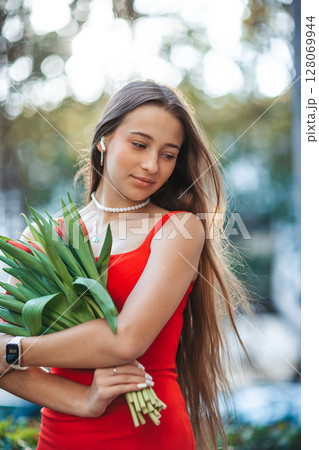 Adorable girl holding bouquet of red tulips in outdoor cafe 128069944