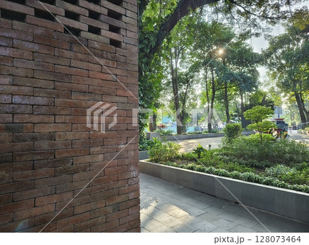 a shady park in summer with green trees and natural red brick buildings-Kediri, Indonesia june 03 2023 128073464