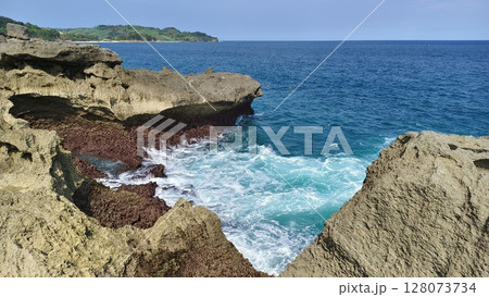 A stunning view of a rocky coastline with the ocean stretching to the horizon under a clear blue sky. Kedung tumpang beach in Tulungagung indonesia 128073734
