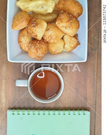 Bolang baling, Odading, fried bread in cubes or blocks, with a light brown crunchy outer skin and sprinkled with sesame seeds with cup of tea on wooden table 128073742