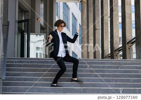 Excited businessman in celebration at steps walking after job interview, promotion, dancing, success Excited businessman in celebration at steps walking after job interview, promotion, dancing, success 128077160