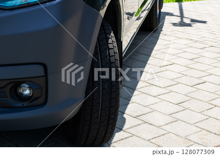 This is a closeup image showing a cars tire resting on a brick driveway 128077309