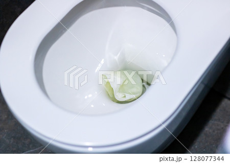 A white toilet featuring a green object resting inside it 128077344