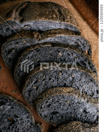 Fresh baked black charcoal sourdough ciabatta bread sliced on wooden board. Fresh baked black charcoal sourdough ciabatta bread sliced on wooden board. 128080989