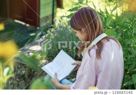 Young woman reading a book in a garden surrounded by lavender Young woman reading a book in a garden surrounded by lavender 128083148