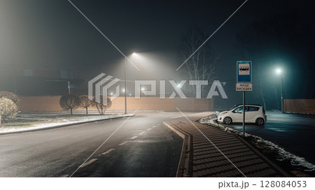 Foggy Night Bus Stop with Lone Car and Streetlights Foggy Night Bus Stop with Lone Car and Streetlights 128084053