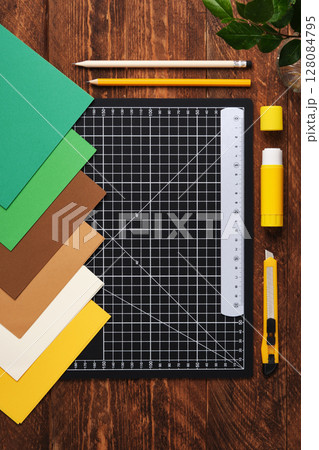 Workspace for paper crafts. Black cutting mat, colored paper, pencils, scissors, ruler, glue. Space for your text. Workspace for paper crafts. Black cutting mat, colored paper, pencils, scissors, ruler, glue. Space for your text. 128084795