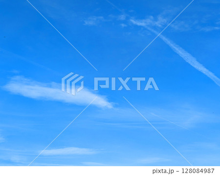 Blue Skies with wispy chemtrail aeroplane lines and fluffy white clouds 128084987