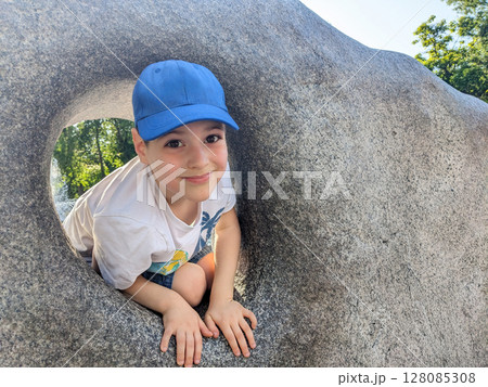 Little boy playing among decorative stones in summer park, space for text Little boy playing among decorative stones in summer park, space for text 128085308