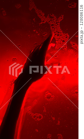 An Artistic Representation of a Hand Emerges Through a Red-Hued Liquid with Bubbles, Evoking Emotions of Depth and Mystery in an Abstract Composition 128086116