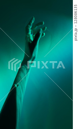 A Captivating Visual Exploration of an Outstretched Hand Bathed in Ethereal Green Light Symbolizing Connection and Expression Through Art 128086135