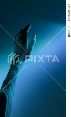 A Mesmerizing Exploration of Light and Shadow: A Hand Reaching Out Towards a Soft Blue Glow Evokes Wonder and Intrigue in the Depths of the Visual Experience A Mesmerizing Exploration of Light and Shadow: A Hand Reaching Out Towards a Soft Blue Glow Evokes Wonder and Intrigue in the Depths of the Visual Experience 128086137