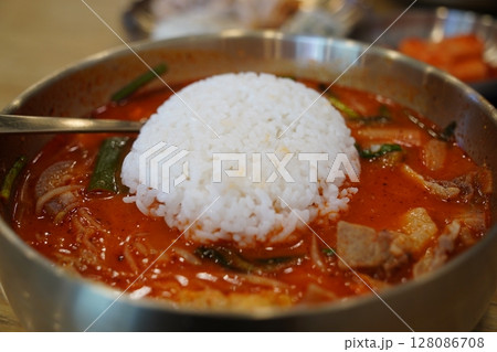 Close-up of Korean Spicy Pork Soup with a Whole Bowl of Steamed White Rice Flipped Onto the Top in a Brass Bowl Close-up of Korean Spicy Pork Soup with a Whole Bowl of Steamed White Rice Flipped Onto the Top in a Brass Bowl 128086708