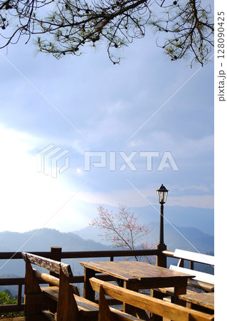 Wooden table outdoor on terrace with classic and vintage black iron street light in valley mountain and blue sky view of local restaurant in countryside of Thailand Wooden table outdoor on terrace with classic and vintage black iron street light in valley mountain and blue sky view of local restaurant in countryside of Thailand 128090425