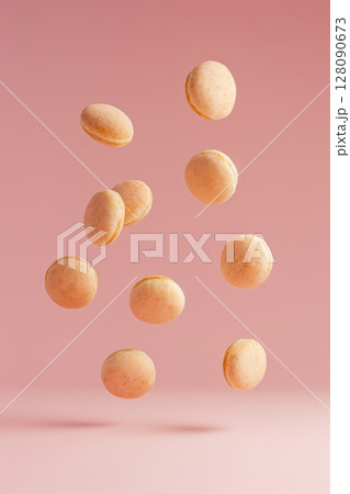 Doughnuts defy gravity as they hover in the air, showcasing their colorful glazes against a pastel pink backdrop, enticing all dessert lovers 128090673